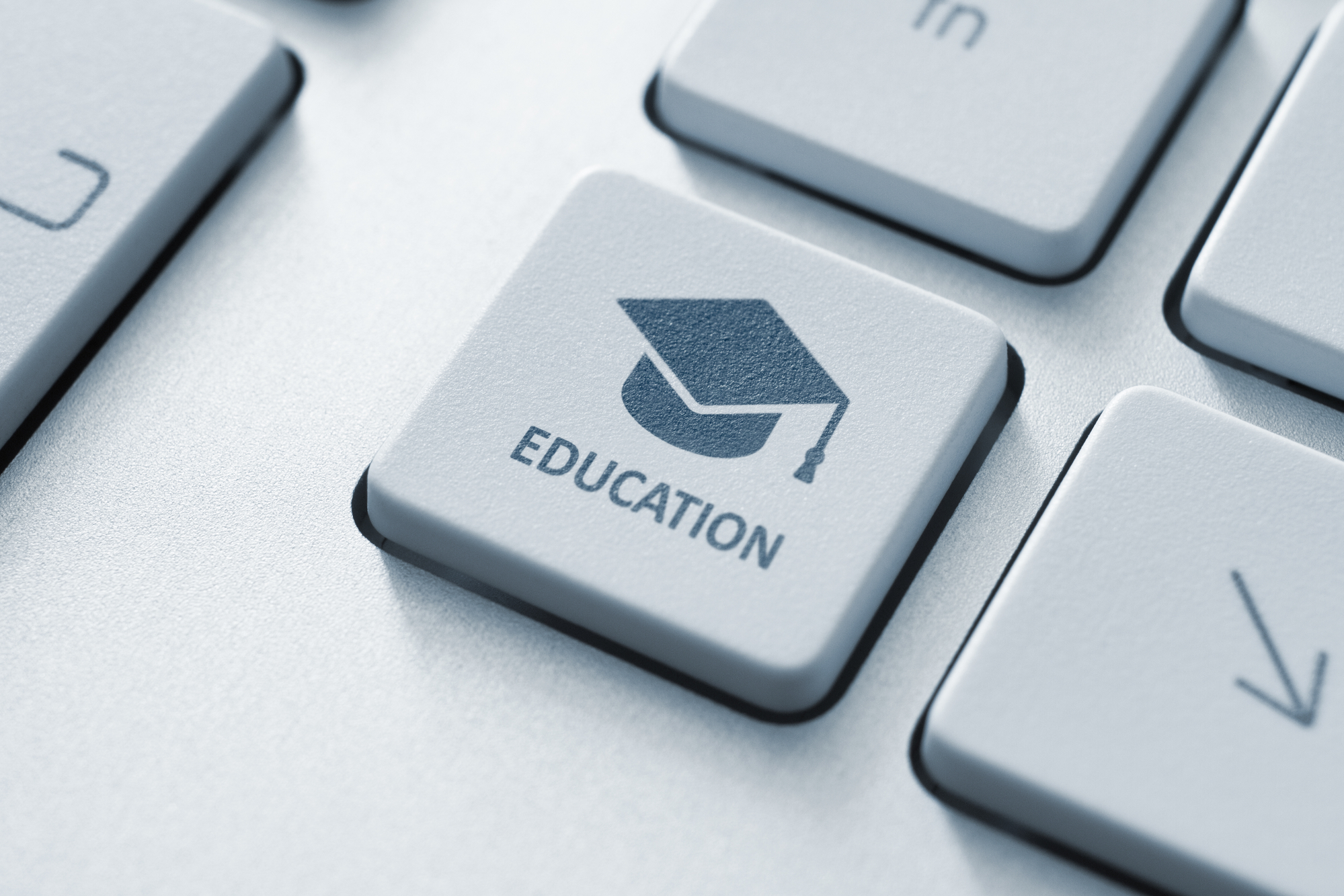 Button with graduation cap icon on a modern computer keyboard. Online education concept.